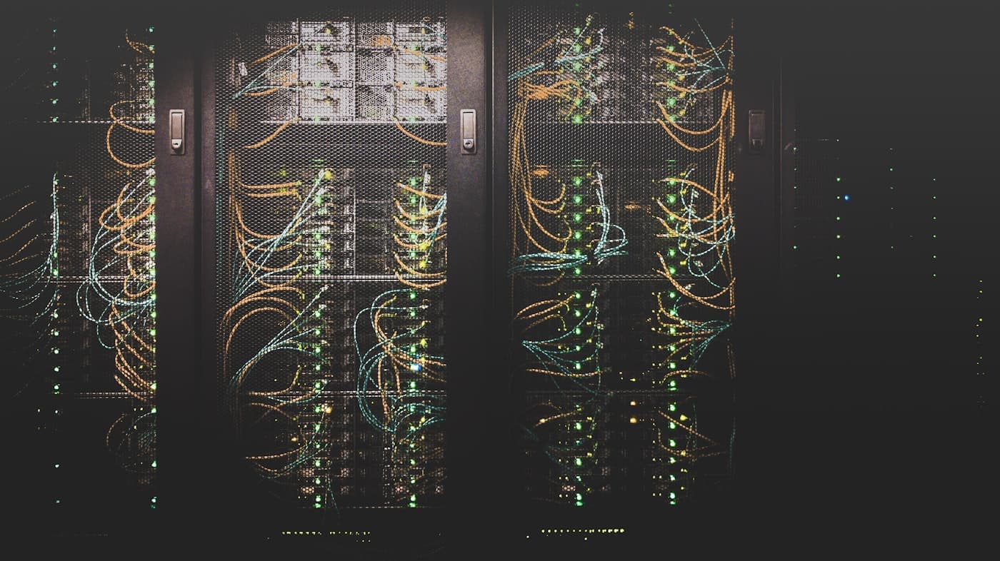 Rows of server racks with cabling in a dim data centre corridor