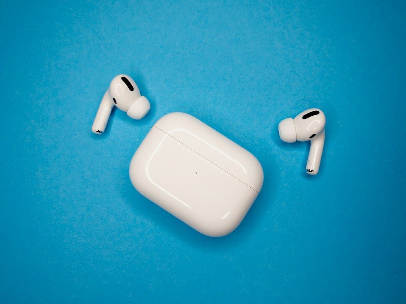 White AirPods Pro earbuds and open charging case on a blue background