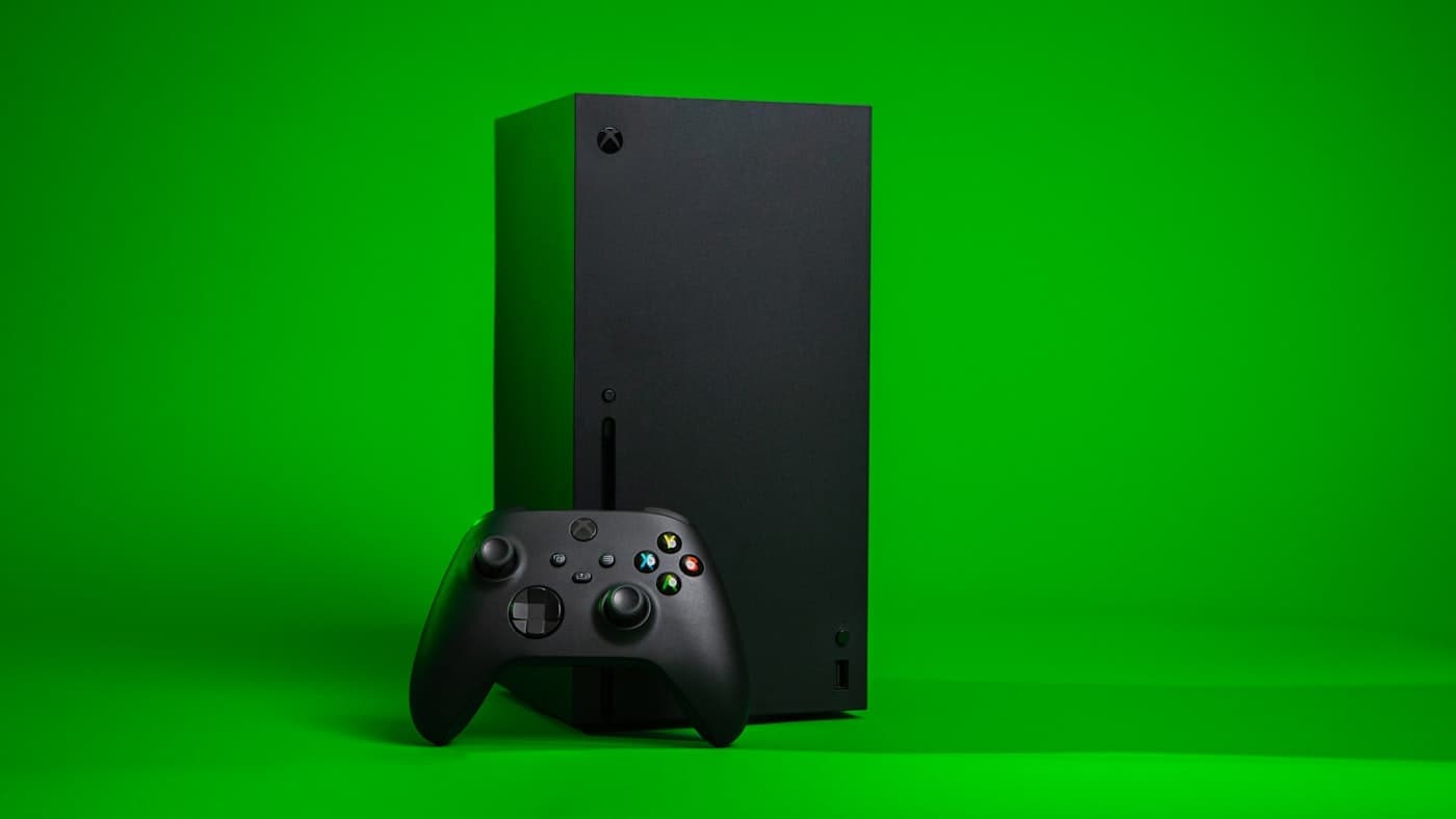 Black Xbox Series X tower with a wireless controller on a green background